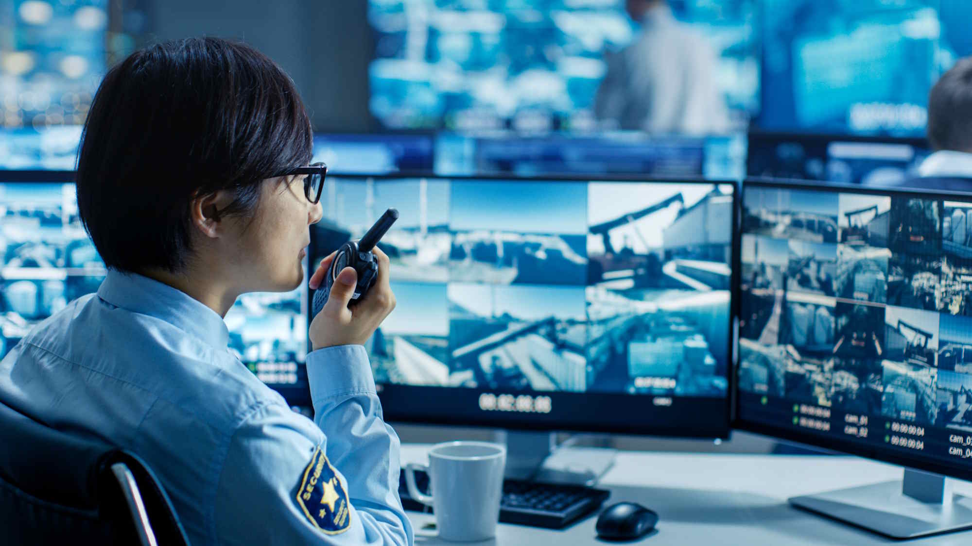 Security officer monitoring multiple surveillance camera feeds in a control room