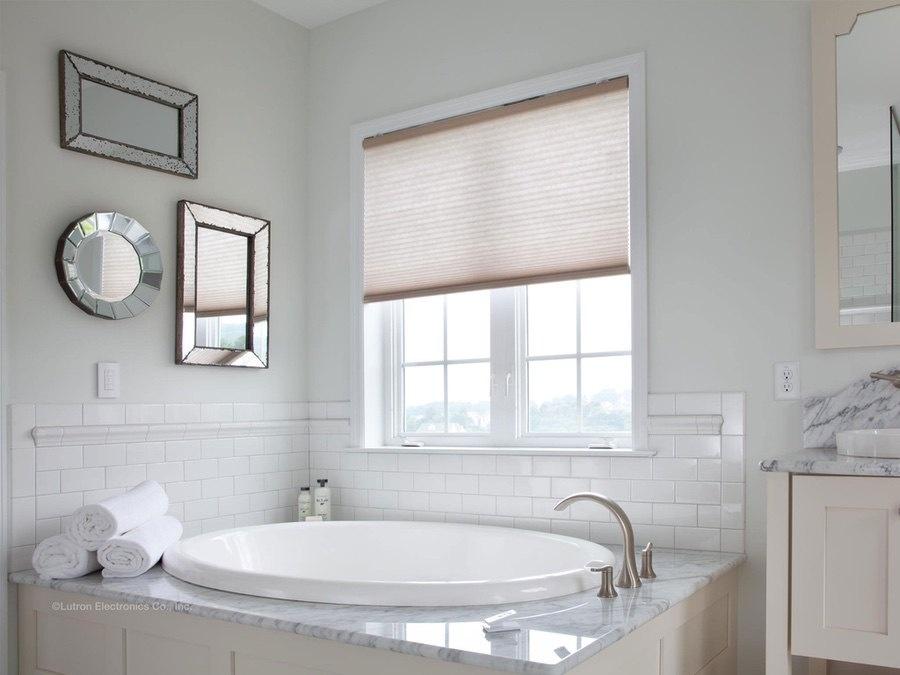 A well-lit bathtub positioned in front of a large window, with neatly arranged towels and decorative mirrors on the walls, creating a bright and inviting bathroom ambiance.