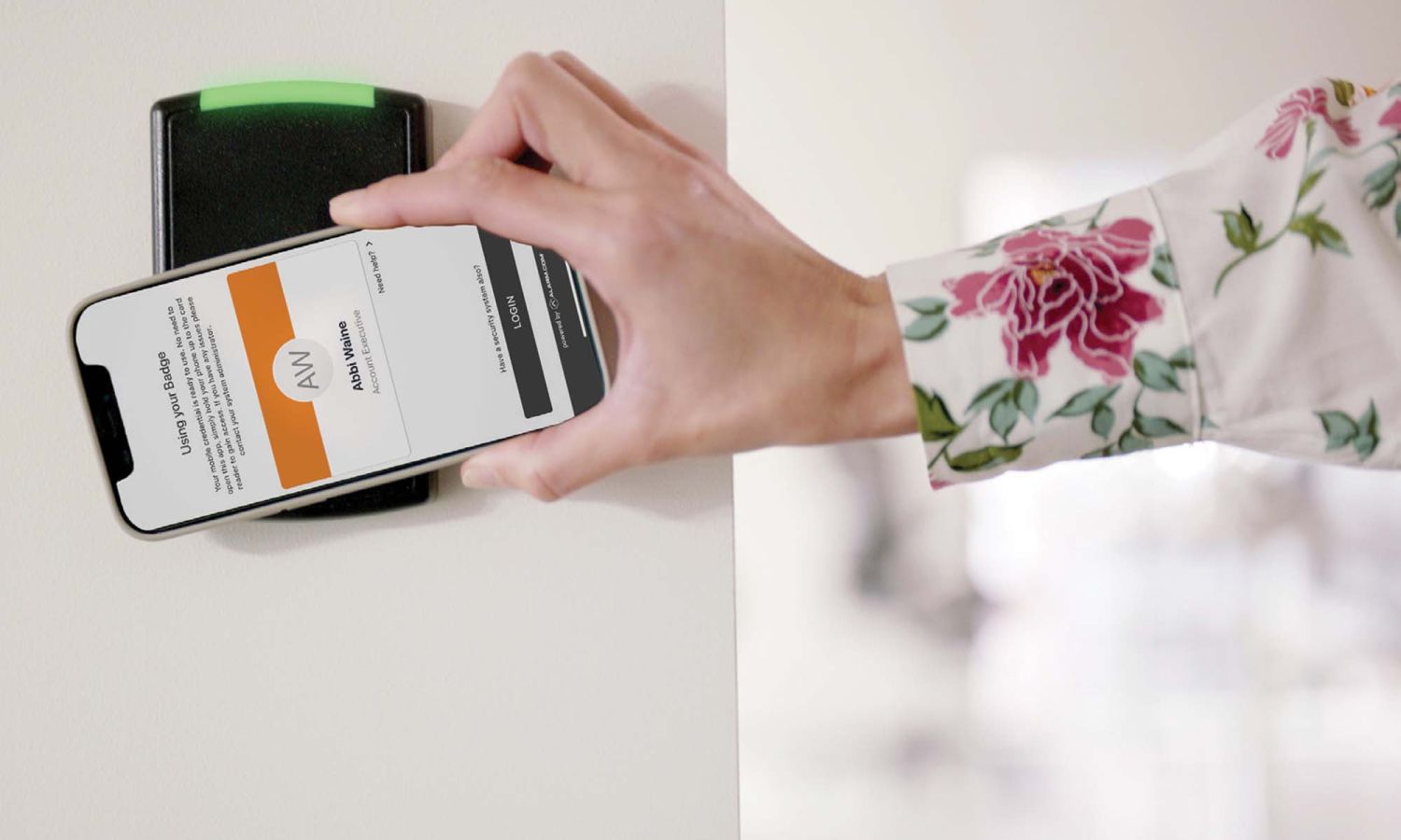 A person using a smartphone to access a wall-mounted security card reader, demonstrating mobile-based access control for secure entry.