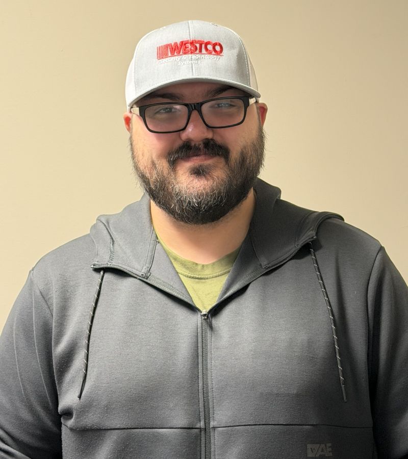 A man wearing a black jacket, grey cap, and glasses.