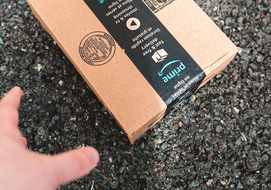 Burglar’s hand reaching for an Amazon box left on a porch