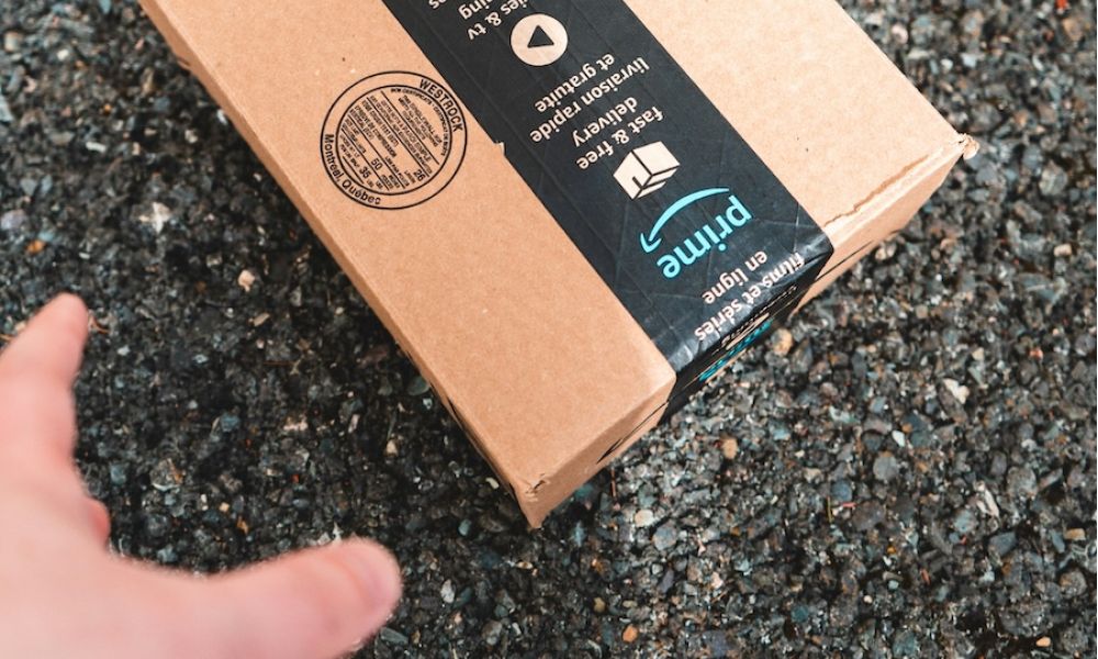 Burglar’s hand reaching for an Amazon box left on a porch