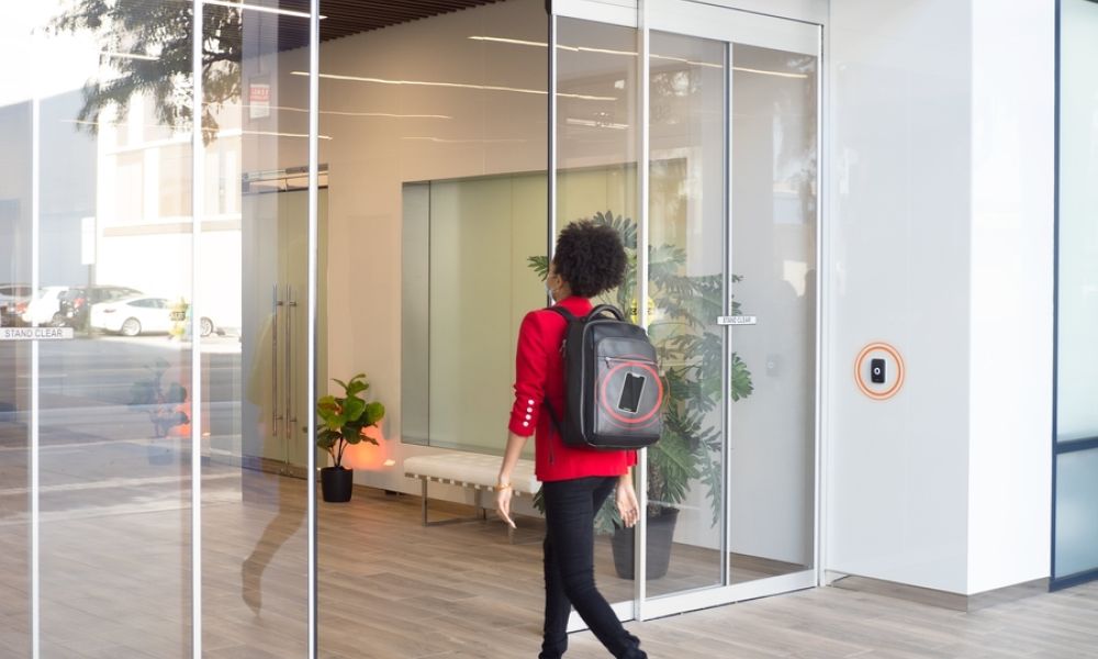 A person walking into a building, gaining access from a smartphone in a backpack.