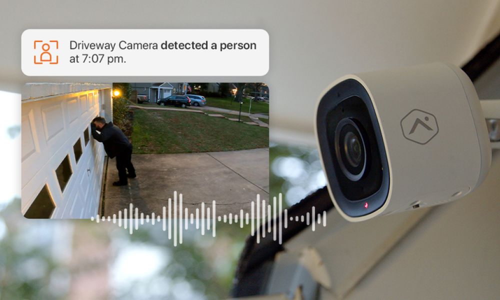 Alarm.com outdoor surveillance camera with an inset of a burglar looking into a garage window