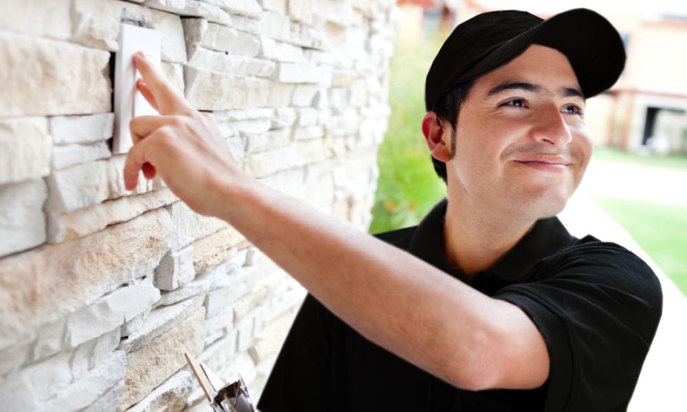 Image is of a security installer testing a system outside a home.