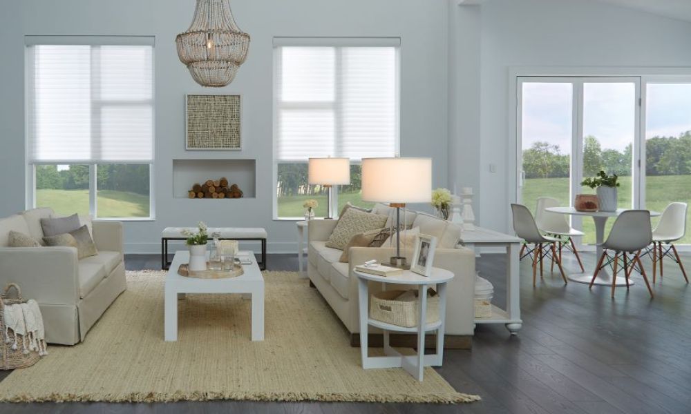 A living area with soft lighting and shades halfway drawn. The windows look out over the countryside.