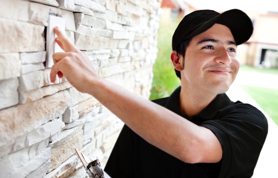 Image is of a person testing a security alarm installed by the front door.